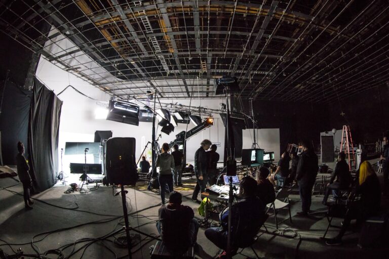 A film crew working on a large soundstage with lighting equipment and cameras